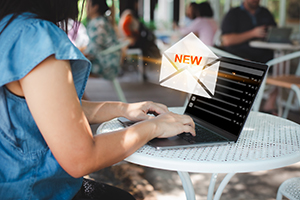 New email notification alert. Woman using laptop receives a new message on email icons in virtual screen at the cafe. Marketing business digital internet technology.